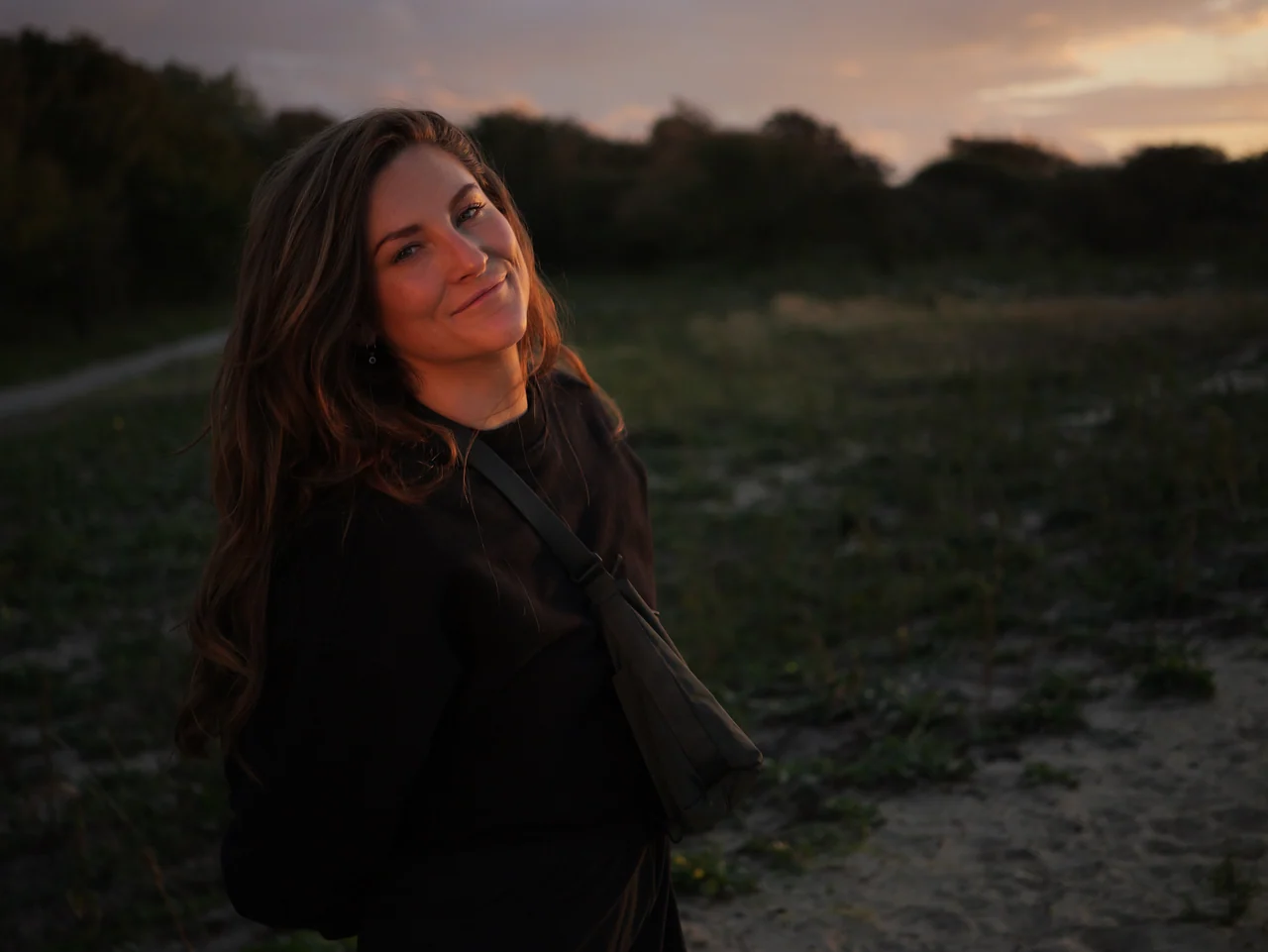 Een vrouw kijkt naar de camera in warm avondlicht