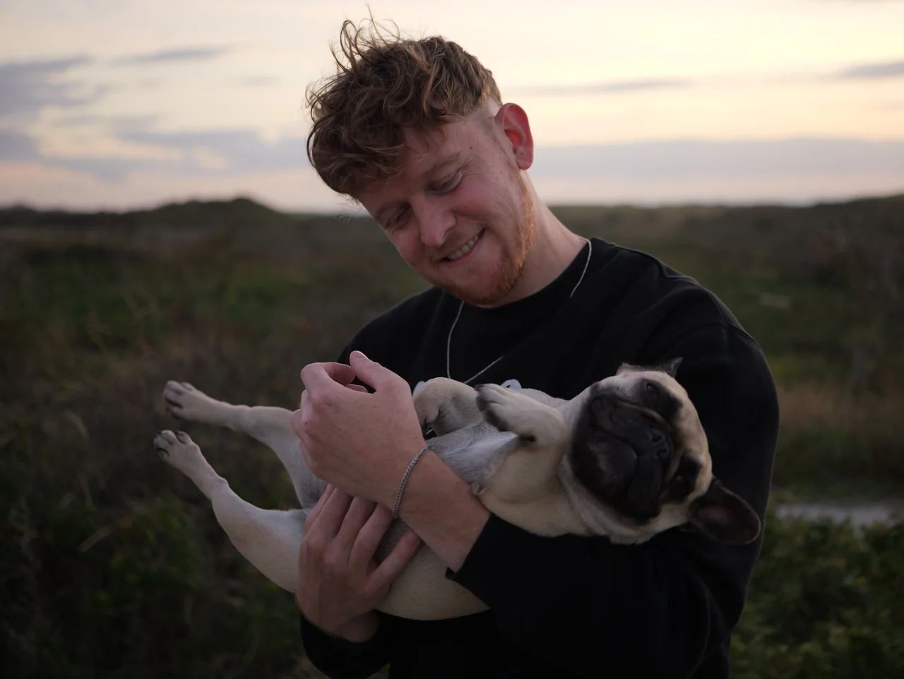 Een man houdt glimlachend een hond in zijn armen